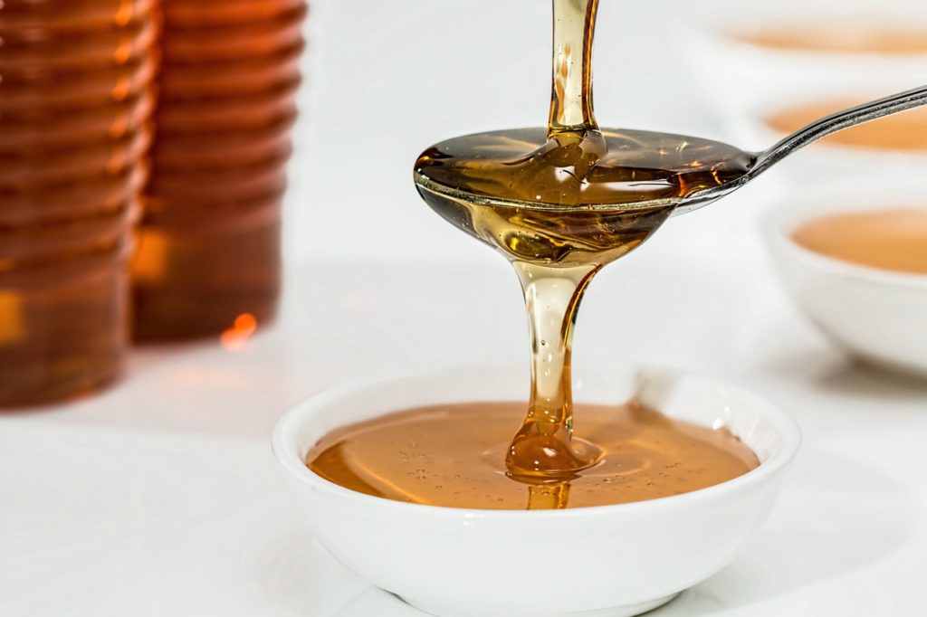 honey pouring into spoon and dripping into bowl
