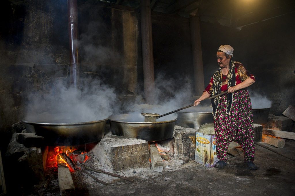 old woman making molasses by boiling cane sugar water