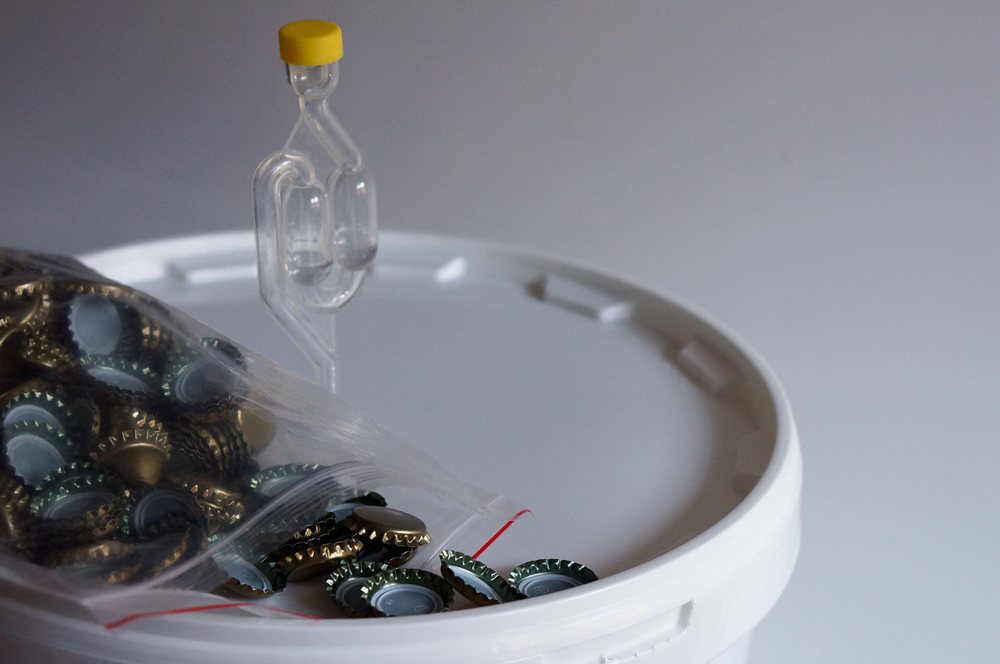 unused bottle caps sitting on top of plastic bucket fermenter