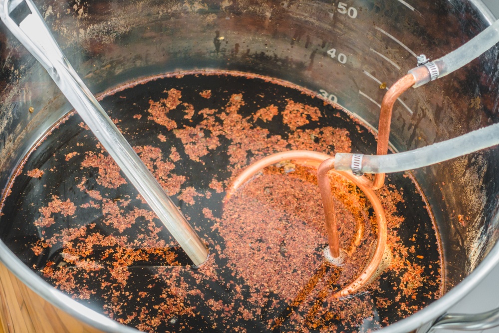 cocoa chili stout being cooled with copper immersion chiller in stainless steel boil kettle